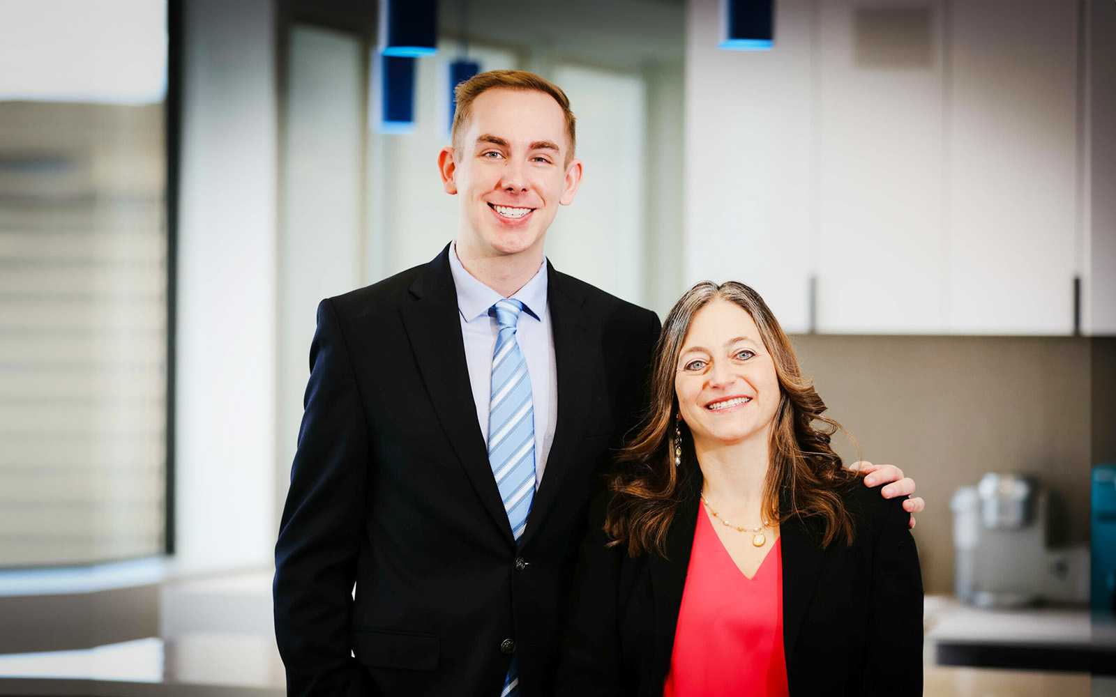 A photograph of a man and woman posing for the camera in an office environment.