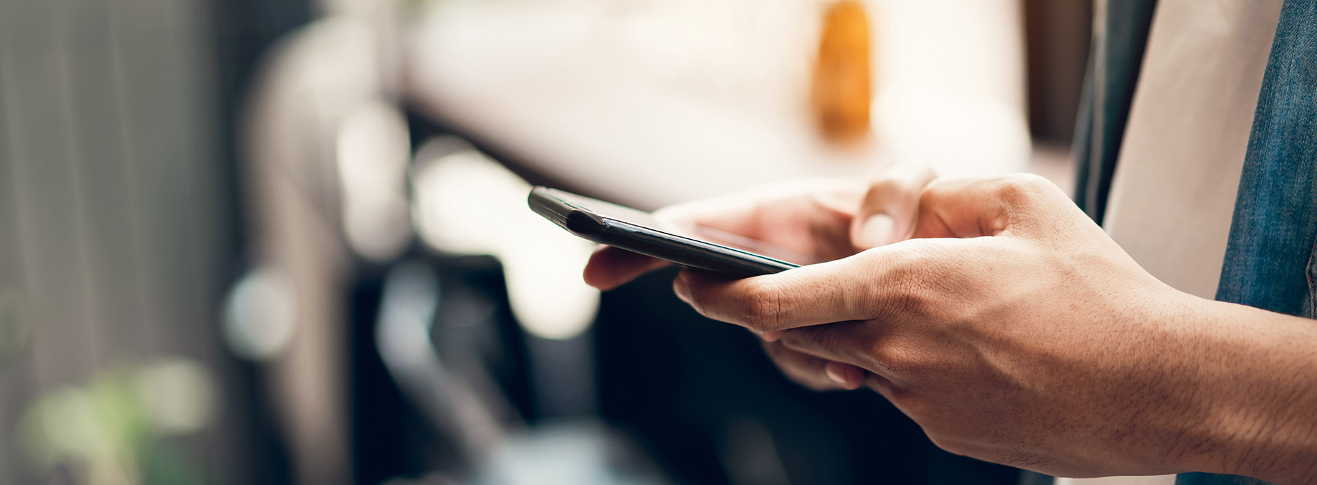 The image shows a person holding a smartphone, with the focus on the phone screen.