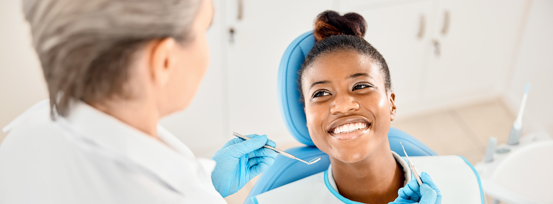 A dental professional in a white coat assisting a patient with a smiling expression during a dental appointment.