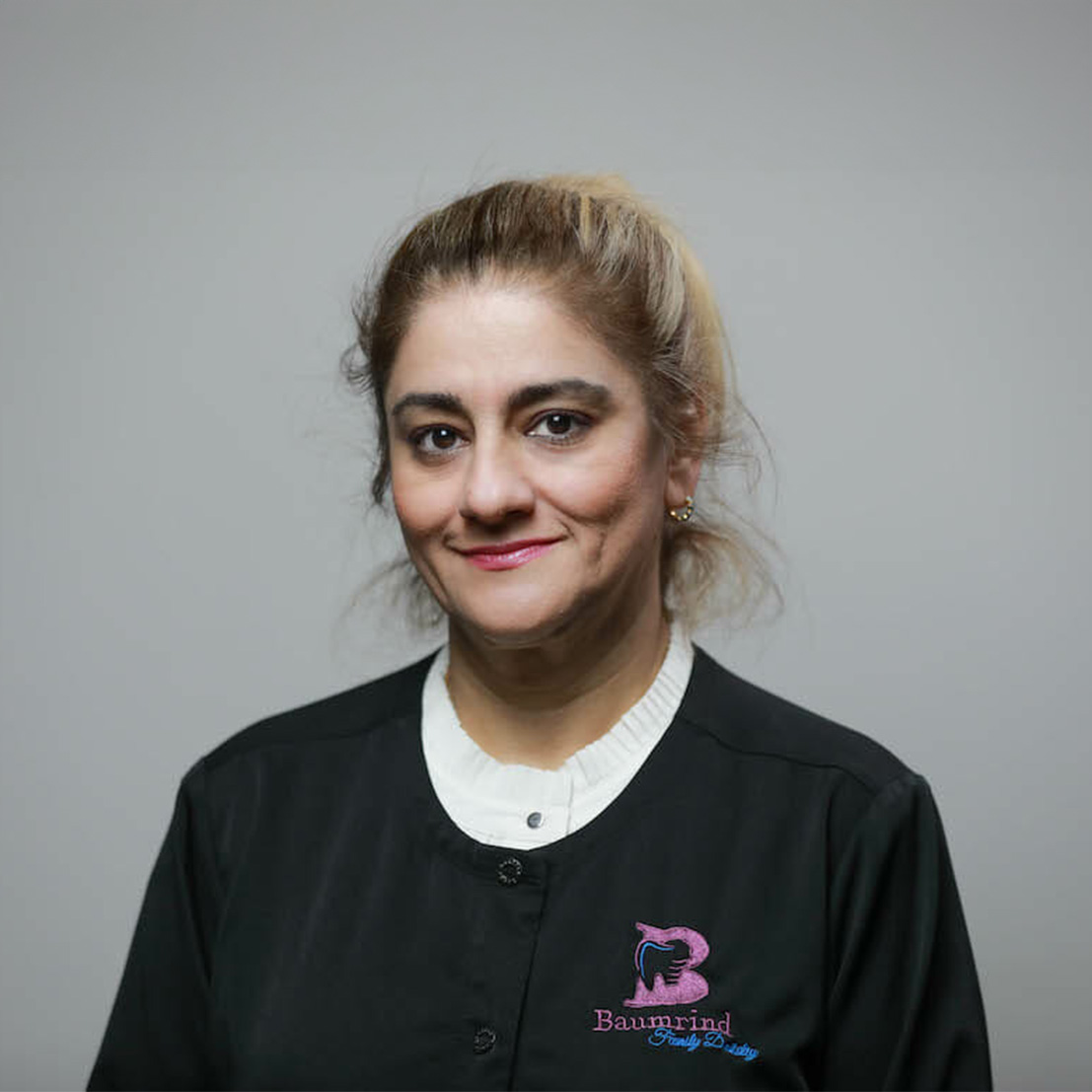 A woman in a black apron is smiling and posing for the photo.