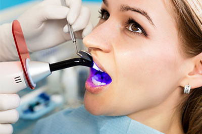 A woman receiving a dental implant procedure, with a dentist using a specialized device to scan her mouth.