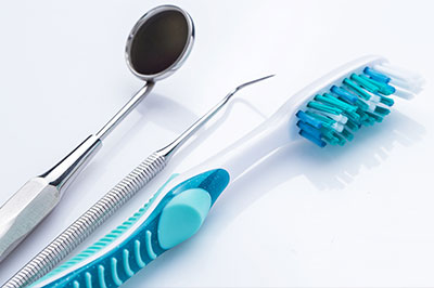 The image displays a collection of dental tools, including a toothbrush and dental instruments, arranged on a white background.