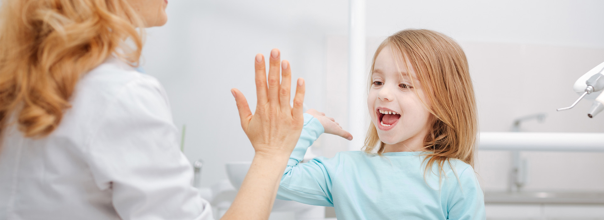 A woman and a young girl are interacting in a bathroom, with the woman appearing to be washing the child s hands.