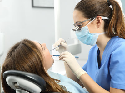 A dental hygienist performing a cleaning procedure on a patient in a dental office.