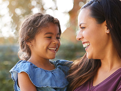 A woman and a young child sharing a joyful moment outdoors.