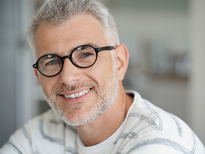 A man with glasses, a beard, and mustache smiling at the camera.