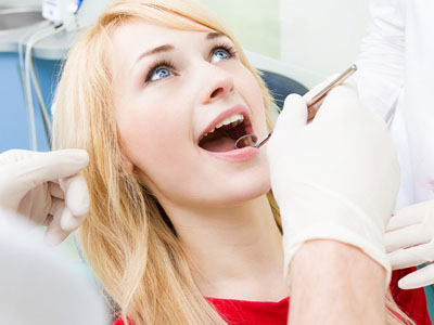 A woman in a dental chair, receiving dental treatment with a smiling expression.