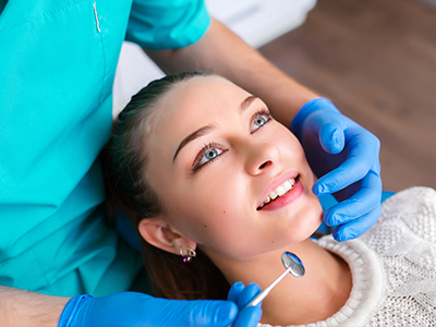 An image of a dental professional performing a procedure on a patient s teeth, with the patient smiling and wearing a protective eye shield.